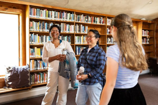 A student showcases the library to two adults.